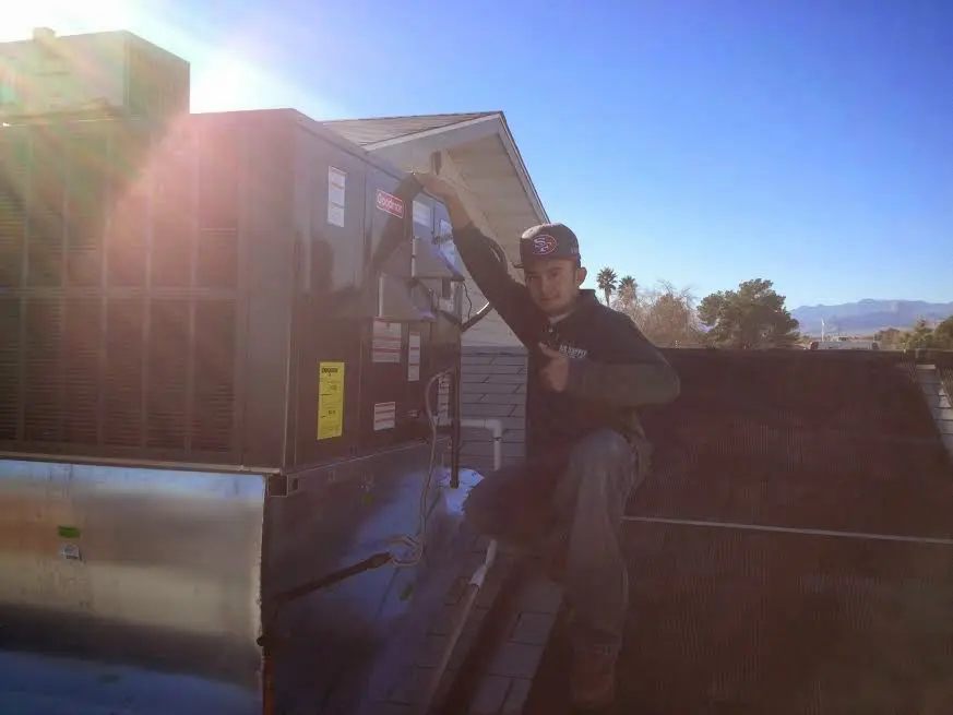 HVAC technician performing Heat Pump Repair on a rooftop unit in Charleston